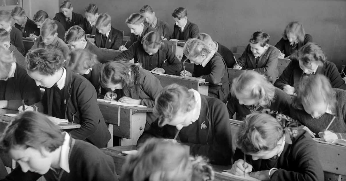 Old style black and white photo of students writing exam
